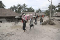 Villagers carry their belonging as they evacuate to a safer place following the eruption of Mount Semeru in Lumajang district, East Java province, Indonesia, Sunday, Dec. 5, 2021. The death toll from eruption of the highest volcano on Indonesia's most densely populated island of Java has risen with scores still missing, officials said Sunday as rain continued to pound the region and hamper the search.(AP Photo/Trisnadi)