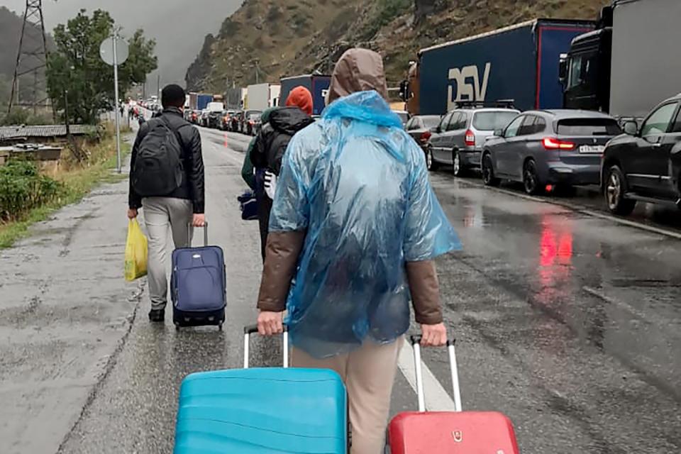 People walk past vehicles with Russian license plates on the Russian side of the border between Georgia and Russia some 20 miles outside the town of Vladikavkaz (AFP/Getty)