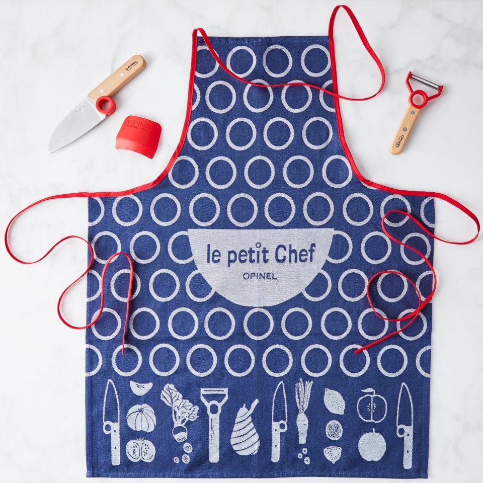 This product image shows a le petit Chef apron and the Opinel’s Le Petit Chef knife set, which received high marks from the folks at America’s Test Kitchen. There are built-in finger rings on the knife and peeler to help kids learn proper holds, as well as a plastic finger guard. (Opinel via AP)