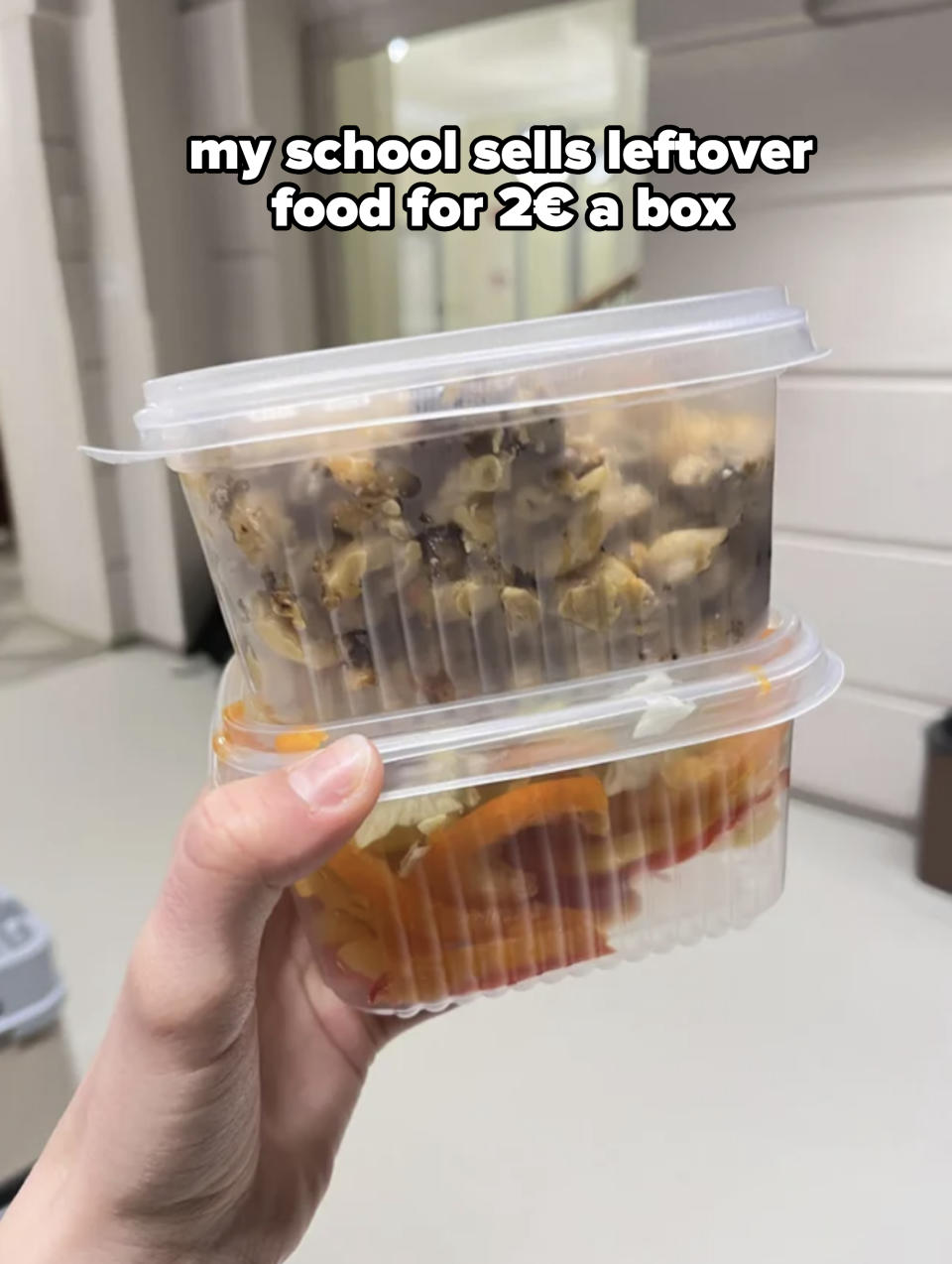 A person holding two stacked transparent food containers with a meal visible inside