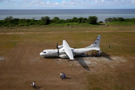 FILE PHOTO: People walk towards a parked Philippine Air Force plane in Philippine occupied Thitu Island in the Spratly Islands in the disputed South China Sea