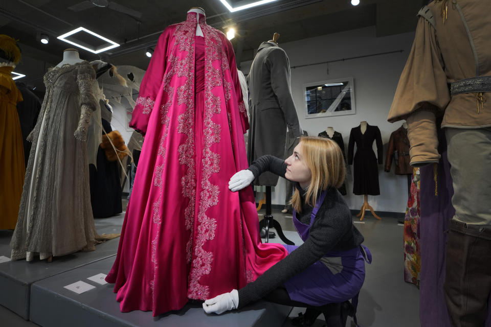 A costume handler arranges Madonna's pink satin evening coat worn in the role of Eva Peron, for the film Evita 1996, as it is displayed at Kerry Taylor Auctions in London, Tuesday, Feb. 27, 2024. The costume estimated at 2,000-3,000 UK Pounds (2,500-3,800 US Dollars) is one of 69 that will be for auction in the Lights Camera Auction event on March 5. The costumes have been donated by Cosprop in support of The Bright Foundation, an arts education charity, established and funded by John Bright, to provide life-enhancing, creative experiences for children and young people facing disadvantage. (AP Photo/Kirsty Wigglesworth)