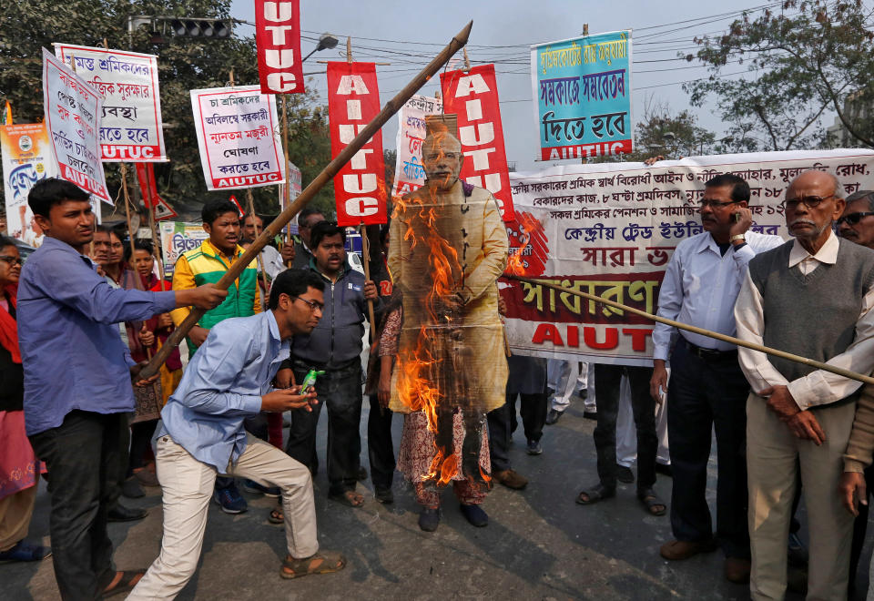 Activists from the All India United Trade Union Centre burn a cut-out depicting India’s PM Modi