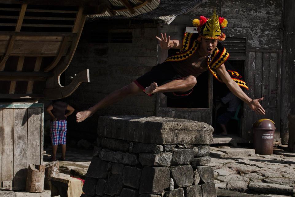 NIAS ISLAND, INDONESIA - FEBRUARY 22: A villager wearing traditional costume jumps over a stone in front of their ancient houses in Bawomataluwo village on February 22, 2013 in Nias Island, Indonesia. Stone Jumping is a traditional ritual, with locals leaping over large stone towers, which in the past resulted in serious injury and death. Stone jumping in Nias Island was originally a tradition born of the habit of inter tribal fighting on the island of Nias. (Photo by Ulet Ifansasti/Getty Images)