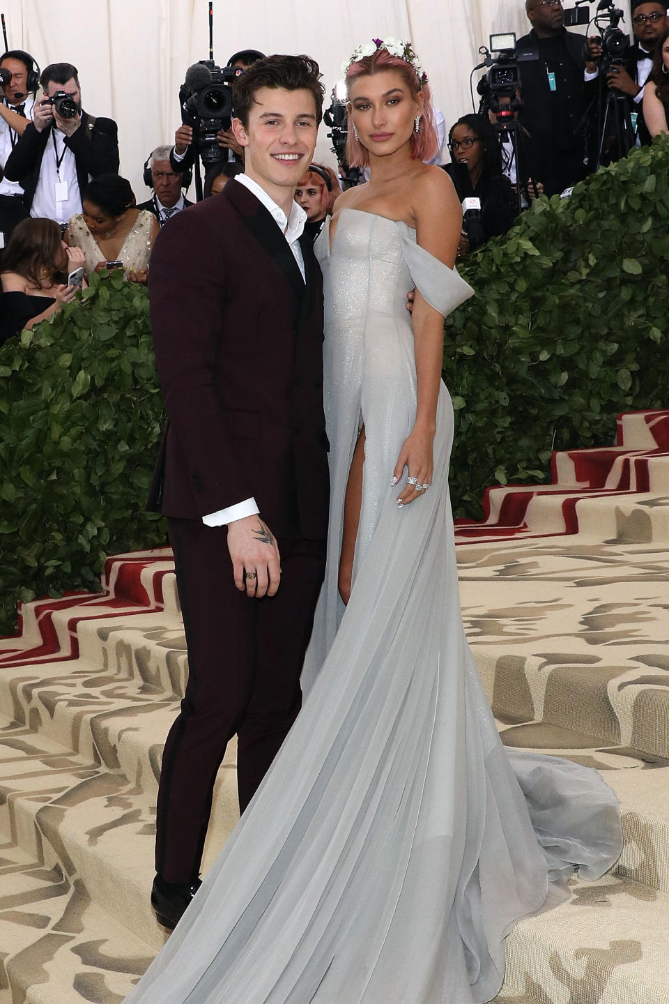 Two celebrities posing together at a gala; one in an elegant off-shoulder gown and the other in a classic suit