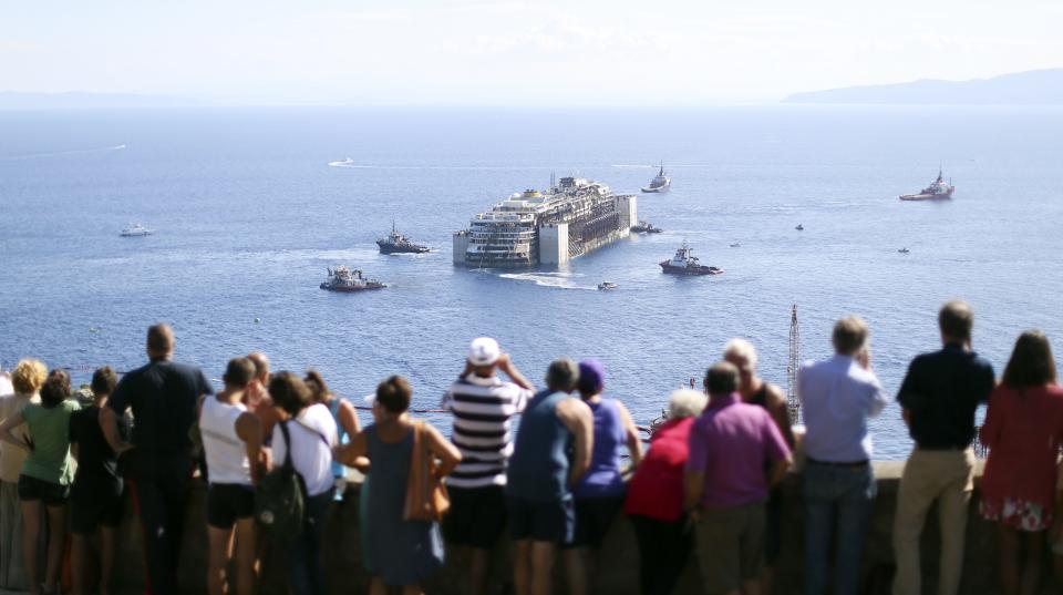 People watch the cruise liner Costa Concordia moving anticlockwise during the refloat operation maneuvers at Giglio Island July 23, 2014. (REUTERS/ Alessandro Bianchi)