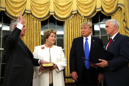 New U.S. Secretary of State Rex Tillerson (L) is sworn in by U.S. Vice President Mike Pence (R) as his wife Renda St. Clair holds a Bible, accompanied by U.S. President Donald Trump during a ceremony at the Oval Office of the White House in Washington, U.S., February 1, 2017. REUTERS/Carlos Barria