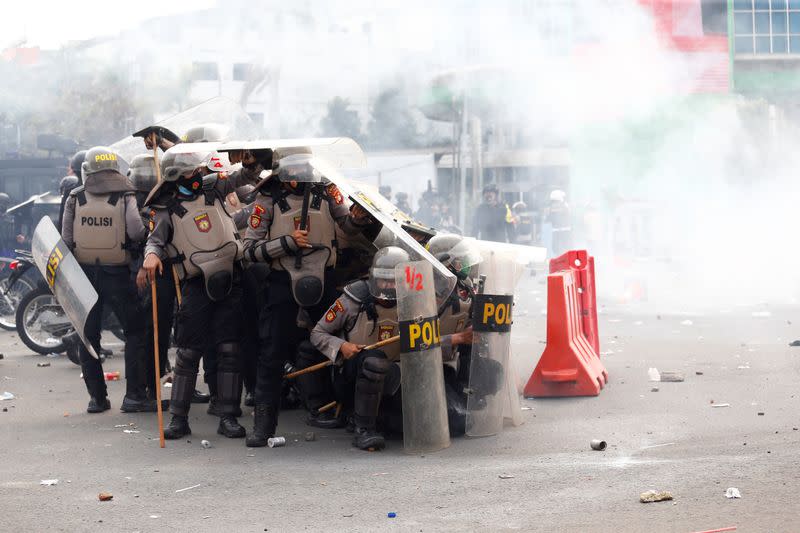 Riot police officers fire tear gas following a protest against the government's labor reforms in a "jobs creation" bill in Jakarta