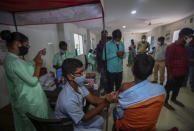 A health worker administers COVID-19 vaccine as other await the turn in Hyderabad, India, Thursday, Dec. 2, 2021. (AP Photo/Mahesh Kumar A.)