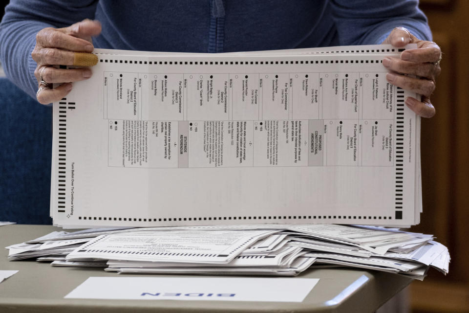 FILE - Officials sort ballots during an audit at the Floyd County administration building in Rome, Ga. on Friday morning, Nov. 13, 2020. On Friday, Nov. 20, The Associated Press reported on stories circulating online incorrectly asserting that the identities of deceased residents in Georgia were used to illegally cast ballots in the 2020 presidential election. (AP Photo/Ben Gray, File)