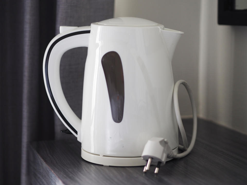 An electric kettle on a table, plug visible, no people in the image