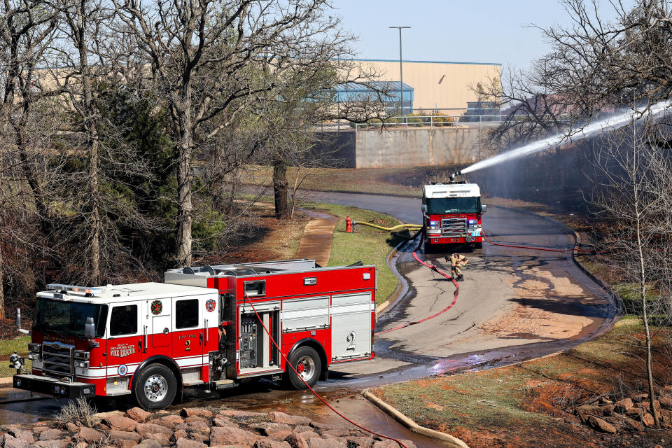 Firefighters hose down trees Friday after a fire broke out near Kelley Avenue and Hefner Road in Oklahoma City during a very windy day.