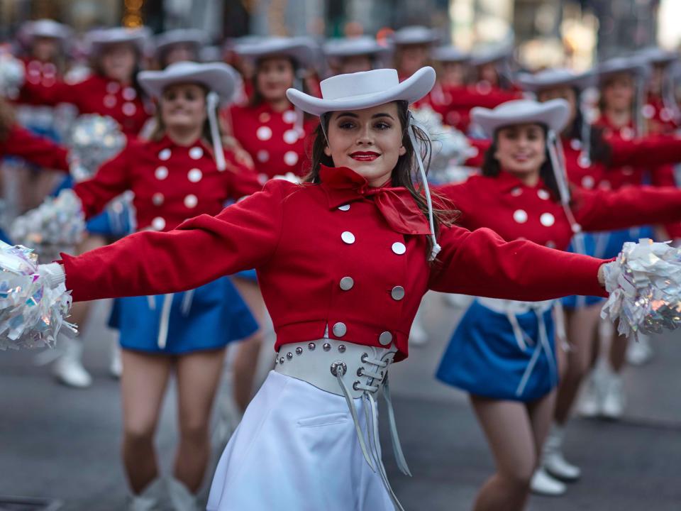 Performers in red and white outfits parade down the street.