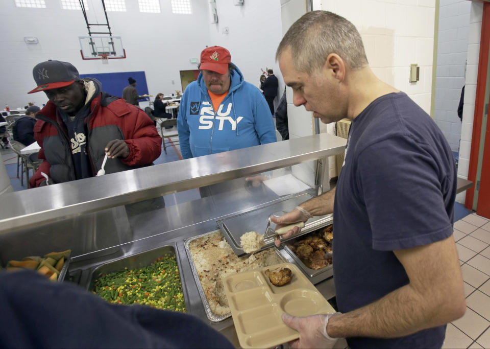 In this Nov. 14, 2013 photo, chef Jeff Ansorge serves up lunch at the Salvation Army Eastside Corp Community Center in St. Paul, Minn. Ansorge, who used to command a staff of 17 at a posh downtown Minneapolis restaurant making nearly $80,000 a year, gave it all up to become the cook in charge of a Salvation Army soup kitchen where the meals are free. (AP Photo/Jim Mone)