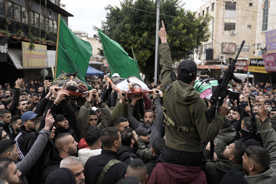 Palestinian gunmen march with bodies of militants draped in the flags of Palestinian Islamic Jihad, killed in an Israeli military raid at Ibn Sina Hospital in the West Bank town of Jenin, Tuesday, Jan. 30, 2024. Armed Israeli undercover forces disguised as women and medical workers stormed the hospital on Tuesday, killing three Palestinian militants. The Palestinian Health Ministry condemned the incursion on a hospital, where the military said the militants were hiding out. (AP Photo/Majdi Mohammed)