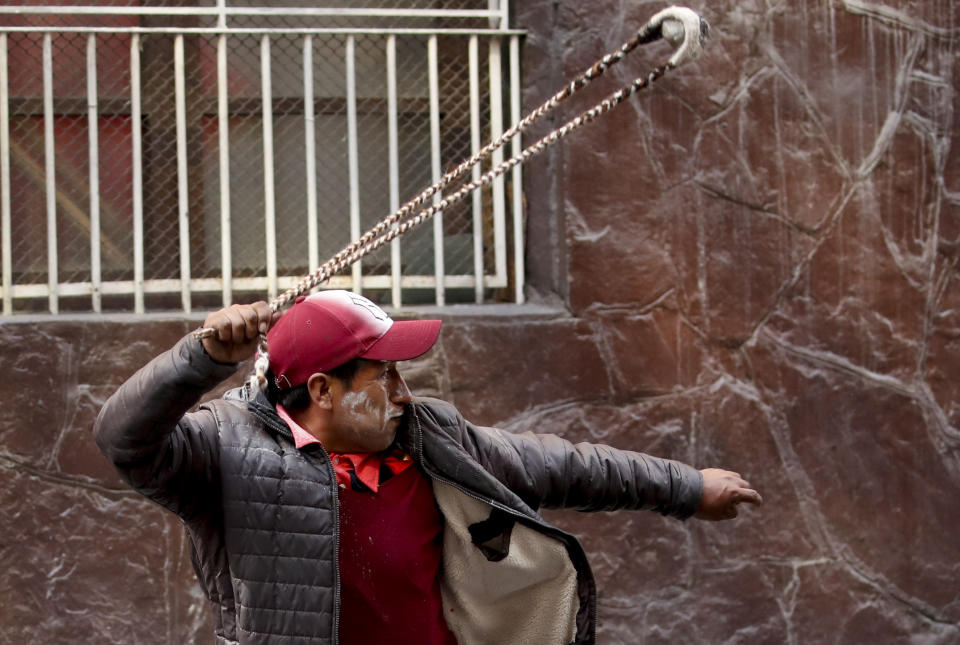A supporter of former President Evo Morales throws a stone to police, in La Paz, Bolivia, Friday, Nov. 15, 2019. Bolivia's new interim president Jeanine Anez faces the challenge of stabilizing the nation and organizing national elections within three months at a time of political disputes that pushed Morales to fly off to self-exile in Mexico after 14 years in power. (AP Photo/Natacha Pisarenko)