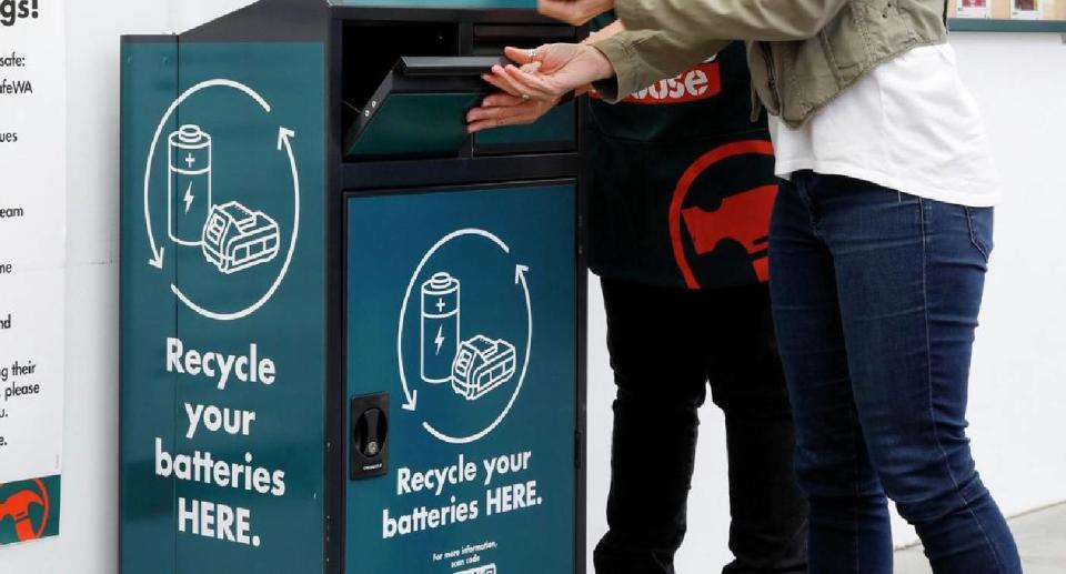 Customer using battery disposal bins with the assistance of a Bunnings team member
