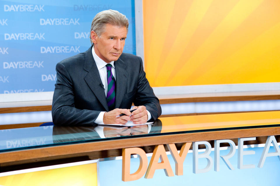 Harrison Ford sits behind a news desk