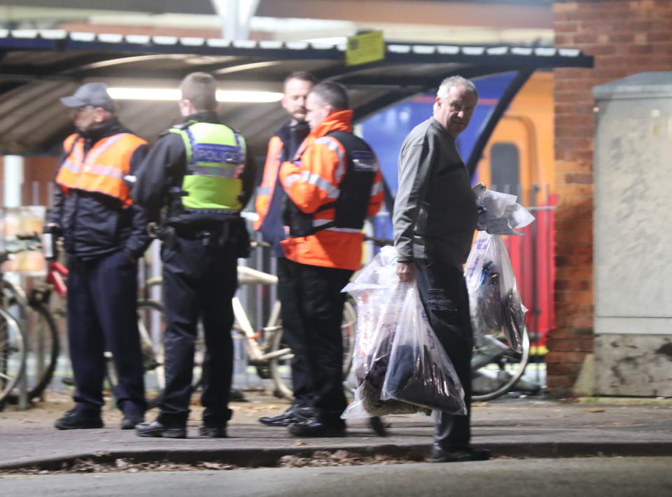 A forensics officer removes items at Horsley station near Guildford, Surrey, after a murder inquiry was launched following the stabbing of a man on board a train in Surrey.