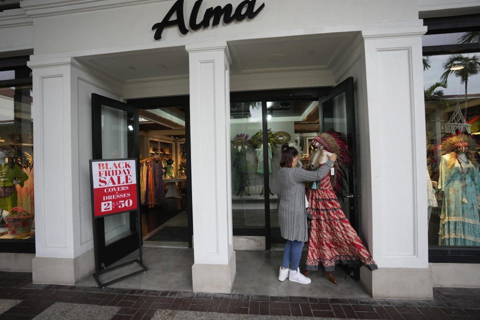 An employee sets up a display, outside a clothing stores advertising sales ahead of Black Friday and the Thanksgiving holiday, Monday, Nov. 21, 2022, in Miami. Retailers are ushering in the start of the holiday shopping season on the day after Thanksgiving, preparing for the biggest crowds since 2019. (AP Photo/Rebecca Blackwell)