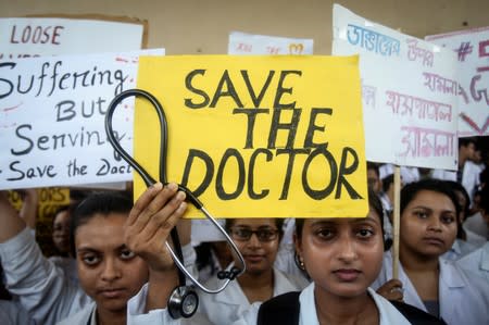 A doctor holds a placard at a government hospital during a strike demanding security after the recent assaults on doctors by the patients' relatives, in Agartala
