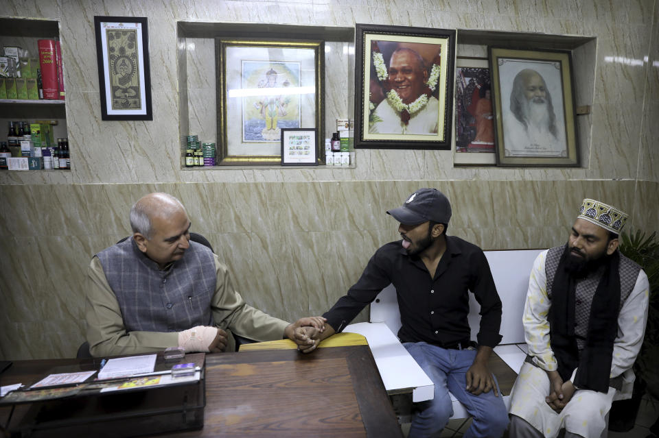 In this Thursday, March 12, 2020, photo, an Ayurvedic doctor checks the pulse of a patient in his clinic in New Delhi, India. With no approved drugs for the new coronavirus, some people are turning to alternative medicines, often with governments promoting them. (AP Photo/Manish Swarup)