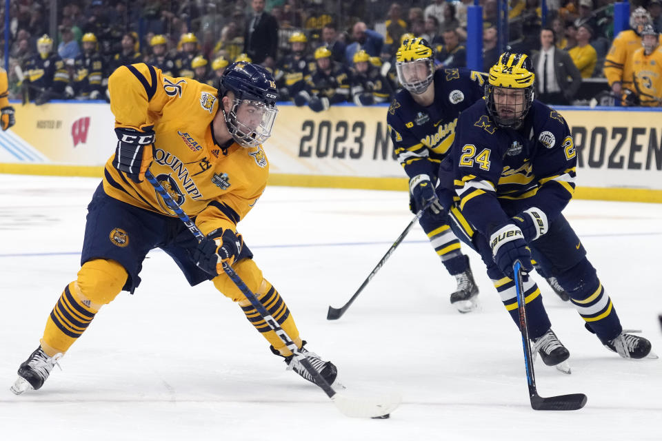 Quinnipiac forward Jacob Quillan (16) passes the puck ahead of Michigan defenseman Steven Holtz (24) during the second period of an NCAA semifinal game in the Frozen Four college hockey tournament Thursday, April 6, 2023, in Tampa, Fla. (AP Photo/Chris O'Meara)