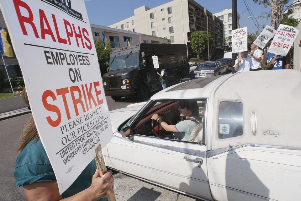 A shopper drives past striking workers as he leaves a Ralphs supermarket in Los Angeles in October, 2003 as more than 70,000 Southern California grocery store workers are on strike.