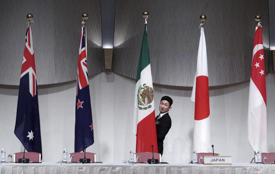 A staff adjusts the Mexican flag prior to a joint press conference of the Comprehensive and Progressive Trans-Pacific Partnership (CPTPP) in Tokyo, Saturday, Jan. 19, 2019. Trade ministers of a Pacific Rim trade bloc are meeting in Tokyo, gearing up to roll out and expand the market-opening initiative. (AP Photo/Eugene Hoshiko)