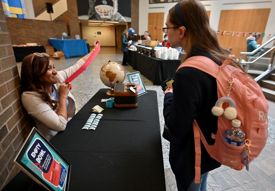 Midaly Carrasquillo Delgado, left, assistant director of Urban Action Institute at Worcester State University, hands raffle tickets to sophomore Ashley Harvey of Dudley during a campus fundraiser to collect money for the university's on-campus food pantry, Thea's Pantry.