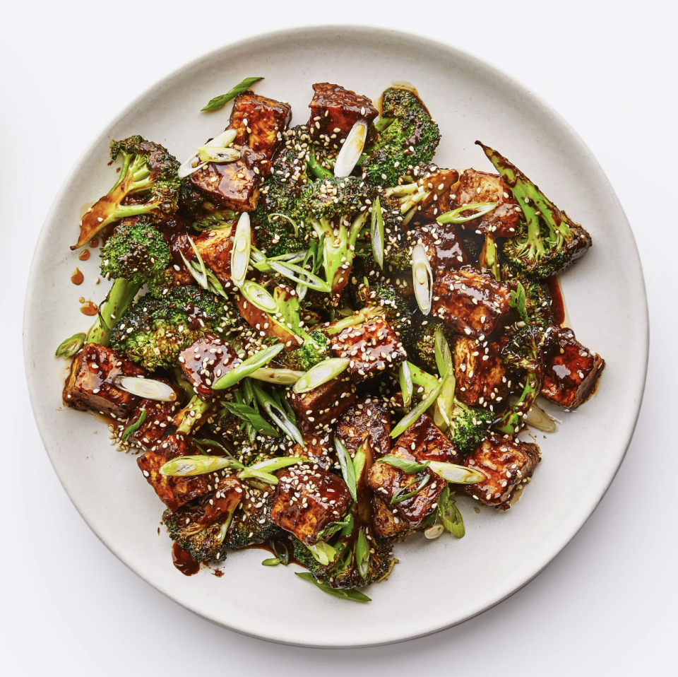 Plate with roasted broccoli and tofu sprinkled with sesame seeds and green onions