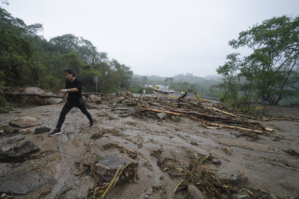 Un hombre cruza una carretera bloqueada por un deslizamiento de tierra provocado por el huracán Otis cerca de Acapulco, México, el miércoles 25 de octubre de 2023. (AP Foto/Marco Ugarte)