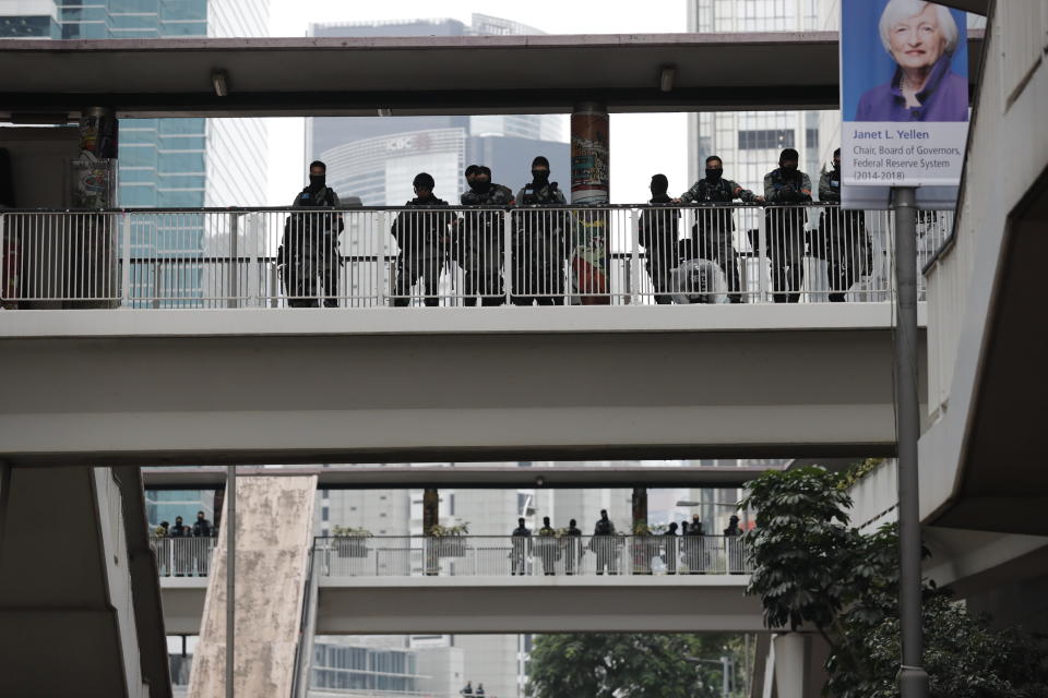 Riot police watch from an overhead bridge as Hong Kong people participate in their annual pro-democracy march to insist their five demands be matched by the government in Hong Kong, Wednesday, Jan. 1, 2020. The five demands include democratic elections for Hong Kong's leader and legislature and a demand for a probe of police behavior during the six months of continuous protests. (AP Photo/Lee Jin-man)