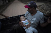 Guillermo Alonso, 54, cradles his 6-year-old grandson Elvin, in the bed of a pickup truck as they leave the site where his home once stood, in the hillside village of La Reina, Honduras, Thursday, June 24, 2021. His home was obliterated by a mudslide triggered by Hurricanes Eta and Iota. "We feel sad because we are homeless but the important thing is that the whole family is alive,” said Alonso. (AP Photo/Rodrigo Abd)