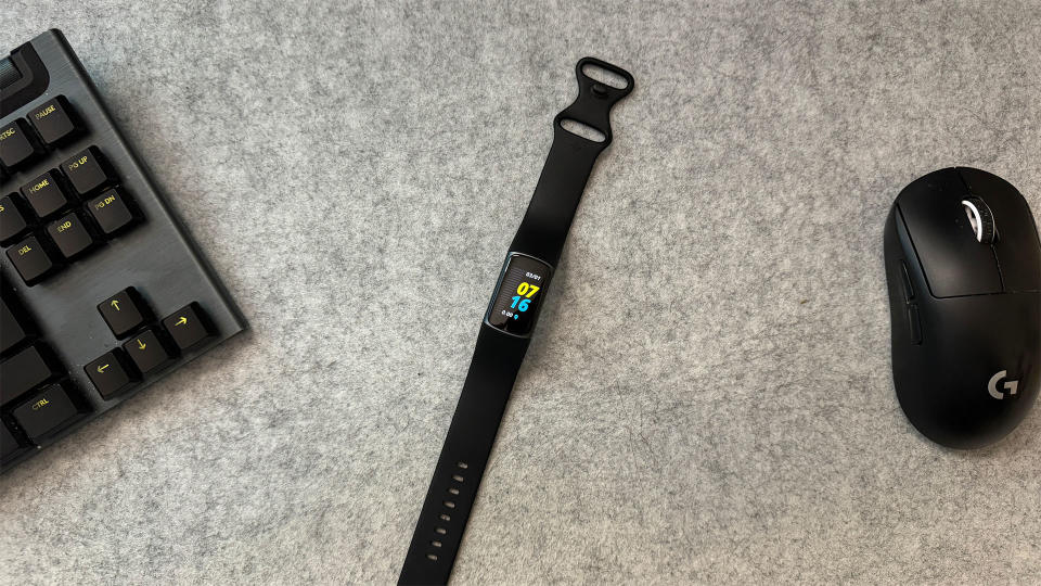Fitbit Charge 5 on grey background next to mouse and keyboard