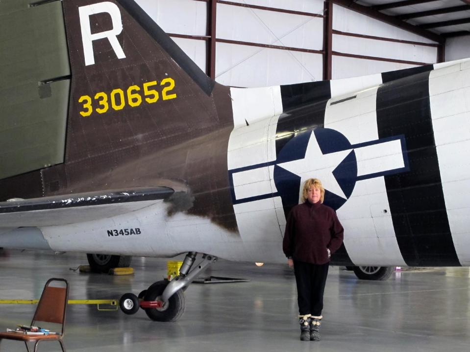 This photo taken March 6, 2014, shows pilot Naomi Wadsworth near a World War II-era Douglas C-47, housed at the National Warplane Museum in Geneseo, N.Y. At the invitation of the French government, the airplane will return to France in June to participate in celebrations marking the 70th anniversary of the D-Day invasion of Normandy. The airplane, known as Whiskey 7 because of its markings, is one of the original troop carriers that dropped paratroopers in advance of the amphibious invasion. In June it will recreate its role and drop paratroopers over the original drop zone in Sainte-Mere-Eglise. (AP Photo/Carolyn Thompson)