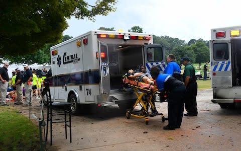 A spectator is taken to an ambulance after a lightning strike on the course which left several injured  - Credit: AP