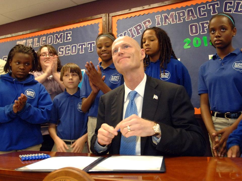 Florida Gov. Rick Scott signs his first bill surrounded by students of the Kipp Middle School, Thursday, March 24, 2011, in Jacksonville, Fla. Far-reaching but divisive legislation that creates a merit pay plan tied to student test scores for Florida teachers while ending tenure for new hires became law Thursday with Scott's signature. (AP Photo/The Florida Times-Union, Don Burk)