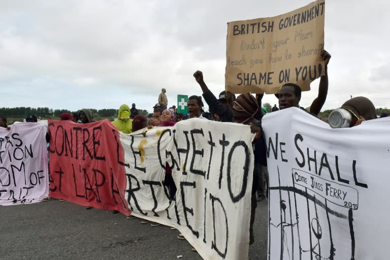 Migrants hold banners including one reading in French "Against the ghetto and apartheid" (L) as they demonstrate in Calais, northern France, on August 5, 2015