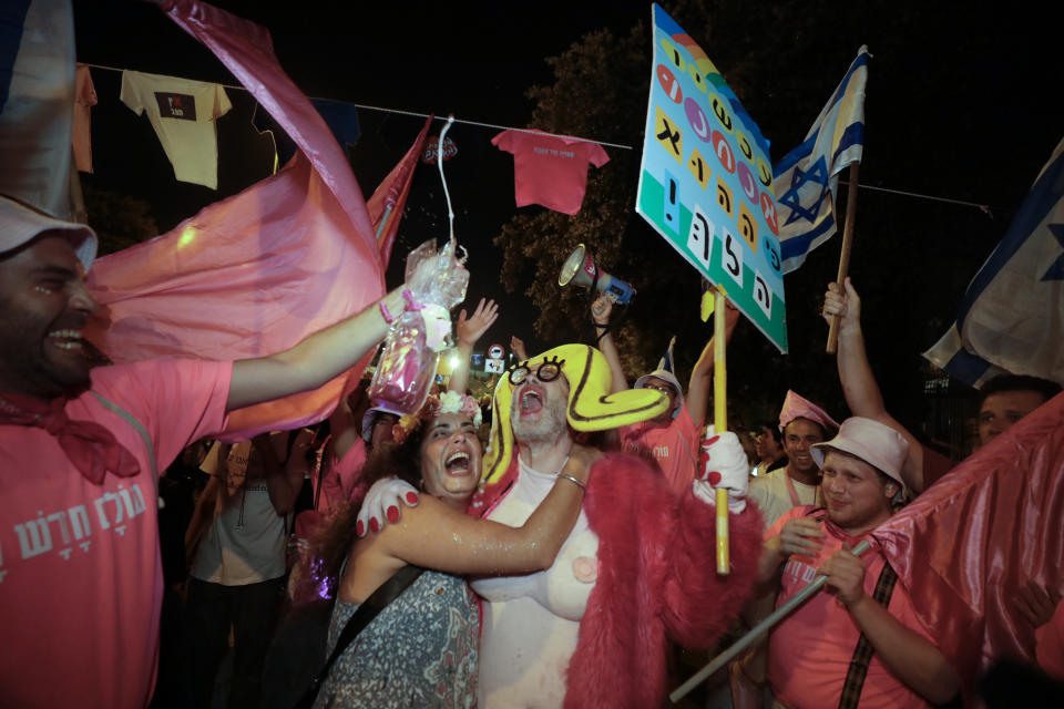 Israelis celebrate the swearing in of the new government in Jerusalem, Sunday, June 13, 2021. Israel's parliament has voted in favor of a new coalition government, formally ending Prime Minister Benjamin Netanyahu's historic 12-year rule. Naftali Bennett, a former ally of Netanyahu, became the new prime minister. (AP Photo/Sebastian Scheiner)