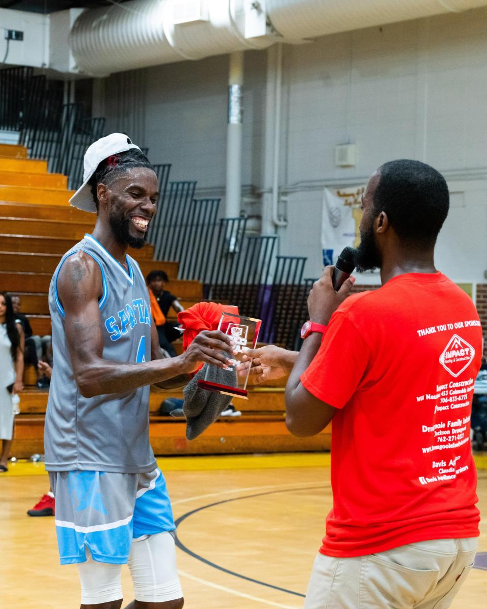 Clash of the Classes Basketball Tournament founder David Beard, right, gives the MVP trophy to Daniel Quarles after a team of Glenn Hill alums defeated a squad of former Laney standouts in Sunday's tournament championship game.