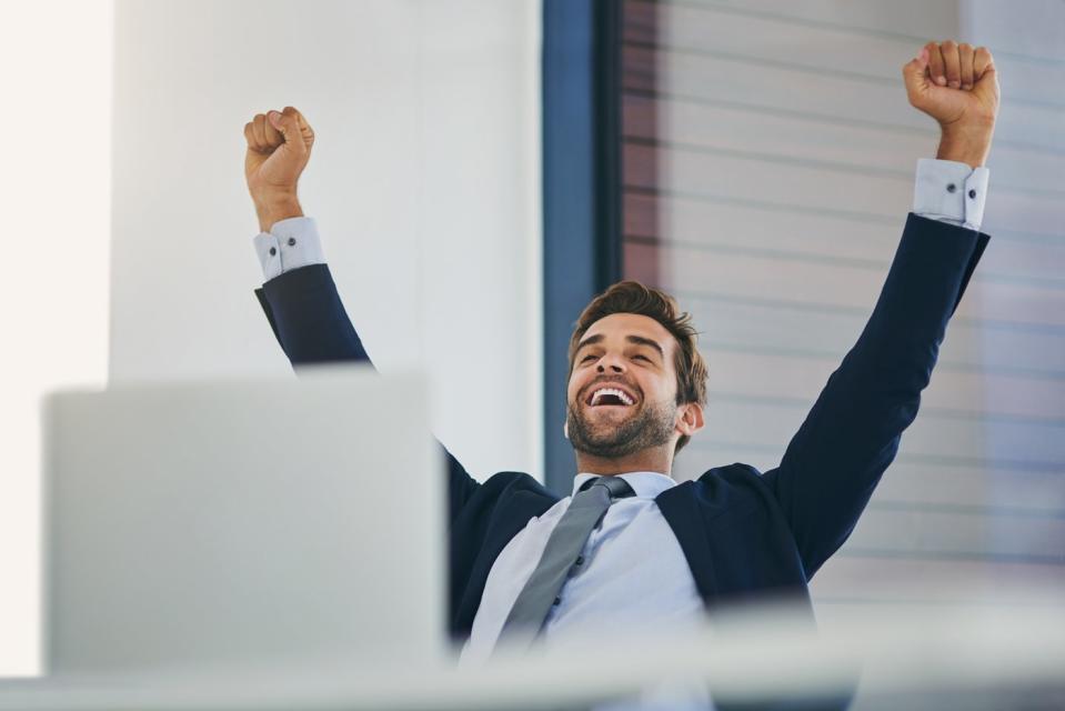 An investor cheers behind a laptop in an office.