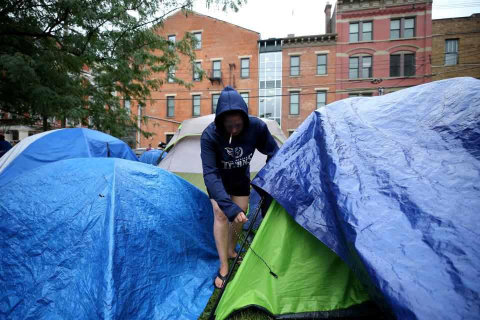 A woman checks on a tarp over her tent on Aug. 16, 2018, at the corner of 13th and Republic Streets in Over-the-Rhine.