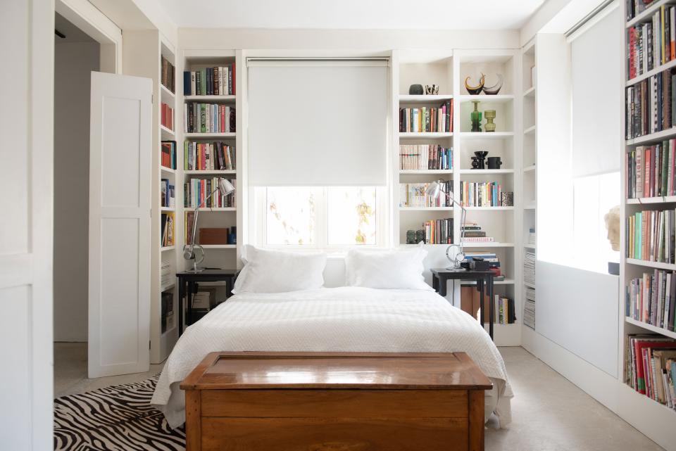 The main bedroom is an intimate studio nook on the second floor, with exposed concrete flooring, a hand-painted wooden library dressed in white oil paint, and a constantly revolving collection of design and cookbooks.