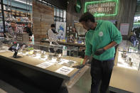 In this photo taken March 24, 2020, budtender Matt Anderson wears gloves as he wipes down a counter at The Reef Capitol Hill, a marijuana store in Seattle. Earlier in the week, Washington Gov. Jay Inslee ordered nonessential businesses to close and the state's more than 7 million residents to stay home in order to slow the spread of the new coronavirus. In Washington and several other states where marijuana is legal, pot shops and workers in the market's supply chain were deemed essential and allowed to remain open. Signs posted at the store said that The Reef is donating 5% of its profits to Seattle-area coronavirus relief efforts. (AP Photo/Ted S. Warren)