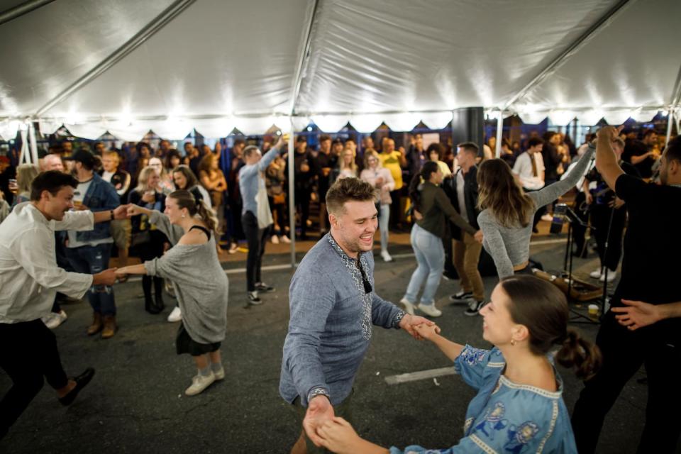 People dance to live music under a tent at the Toronto Ukrainian Festival, in Toronto's Bloor West Village, on Friday, Sept. 16, 2022.