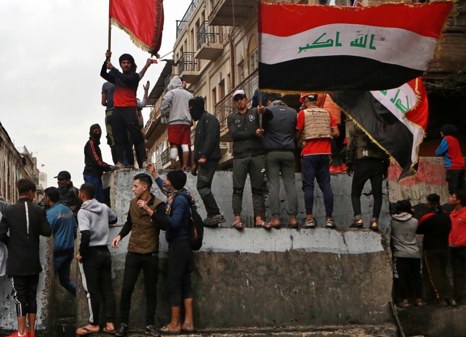 Anti-government protesters gather on barriers set up by security forces to close Rasheed Street during ongoing protests in Baghdad, Iraq, Tuesday, Dec. 3, 2019. At least 400 people have died since the leaderless uprising shook Iraq on Oct. 1, with thousands of Iraqis taking to the streets in Baghdad and the predominantly Shiite southern Iraq decrying corruption, poor services, lack of jobs and calling for an end to the political system that was imposed after the 2003 U.S. invasion. (AP Photo/Khalid Mohammed)