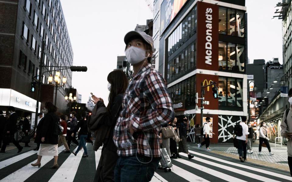 Pedestrians wearing protective masks cross a road in the Shinjuku district of Tokyo, Japan - Soichiro Koriyama 