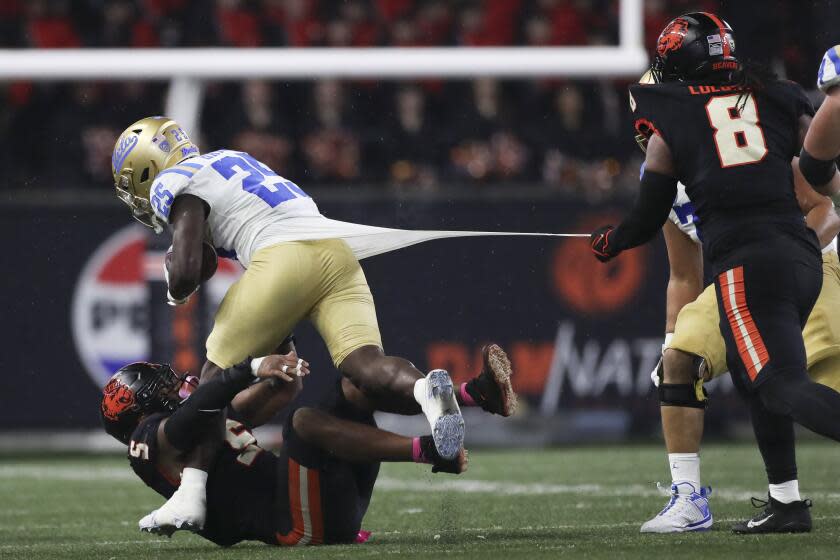 UCLA running back TJ Harden (25) is brought down by Oregon State's Easton Mascarenas-Arnold (5) and Sione Lolohea (8) during the second half of an NCAA college football game Saturday, Oct. 14, 2023, in Corvallis, Ore. (AP Photo/Amanda Loman)
