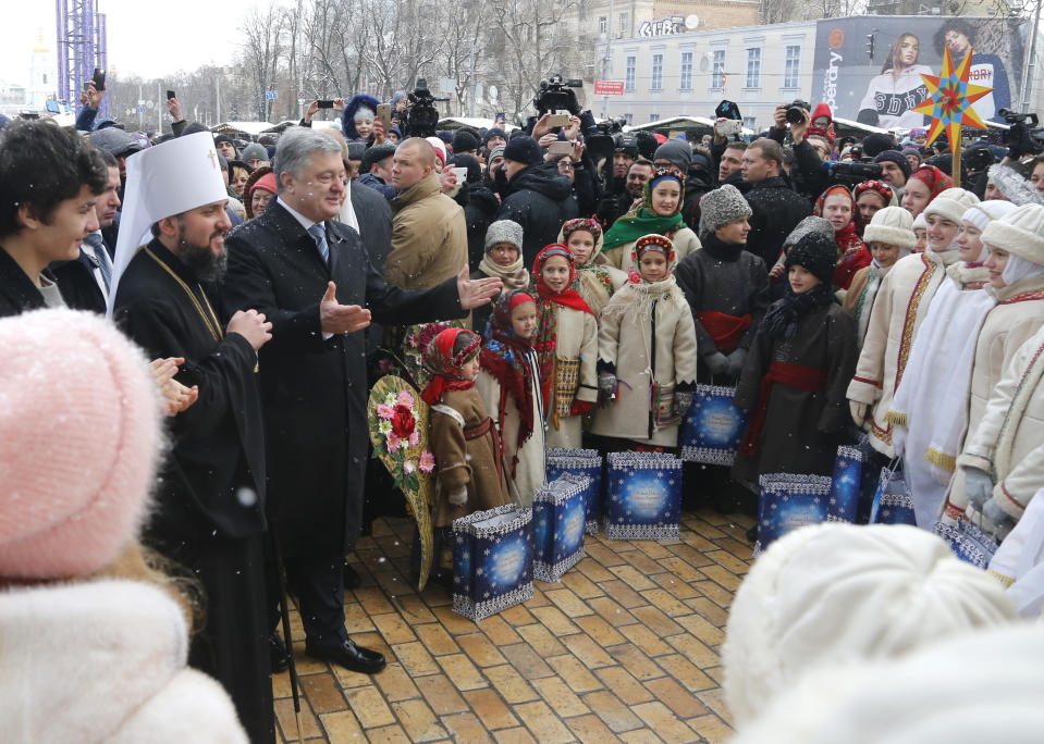 Metropolitan Epiphanius, the head of the independent Ukrainian Orthodox Church, second left, and Ukrainian President Petro Poroshenko react with believers after the service marking Orthodox Christmas and celebrating the independence of the Ukrainian Orthodox Church out of the St. Sophia Cathedral in Kiev, Ukraine, Monday, Jan. 7, 2019. (AP Photo/Efrem Lukatsky)